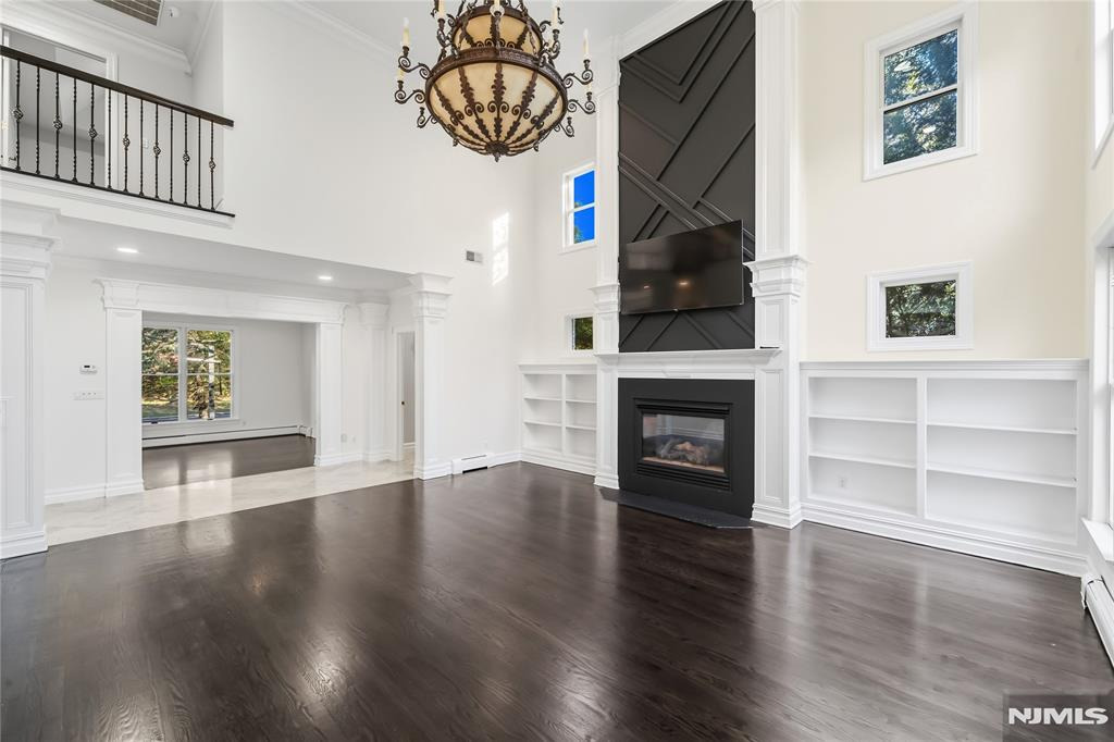 Before — Before and after virtual staging of a two-story great room with seating, area rug, styled built-ins, and greenery