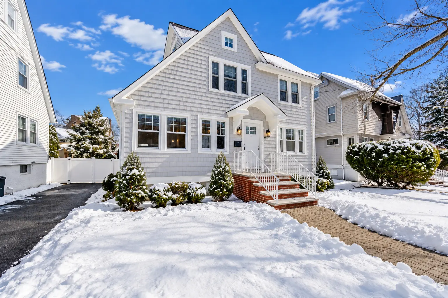 Before and after real estate photo enhancement of a white shingle colonial home changed from a snowy winter scene to a lush summer scene — before