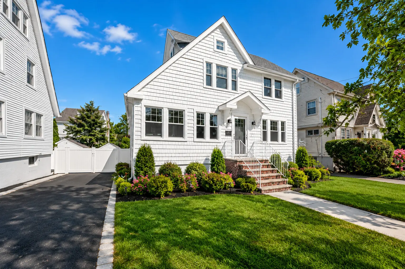 Before and after real estate photo enhancement of a white shingle colonial home changed from a snowy winter scene to a lush summer scene — after